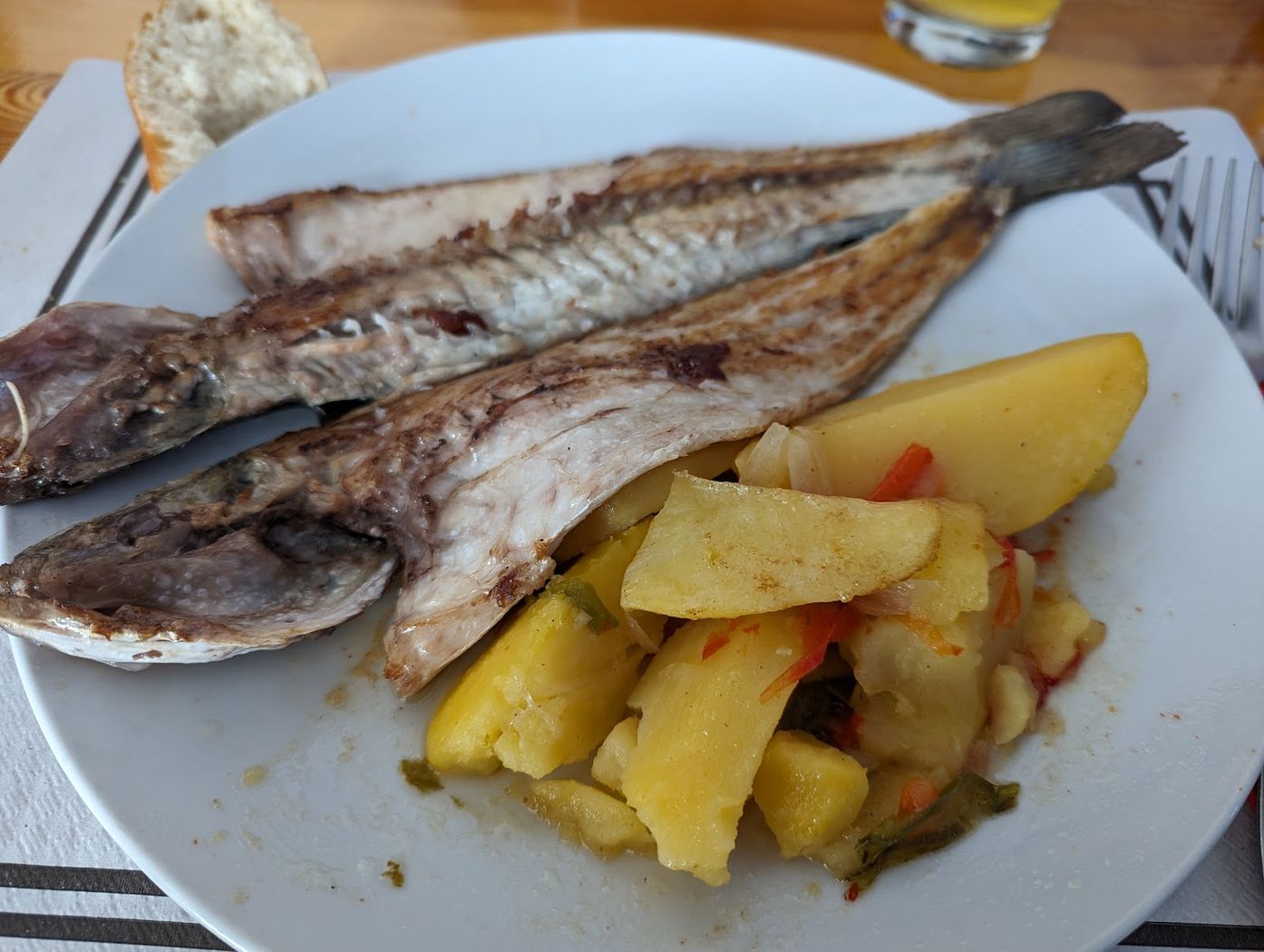 Pescado a la plancha servido con patatas y pimientos salteados.